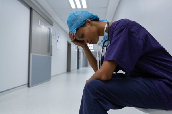 tensed surgeon with hand on forehead sitting in corridor of the picture id