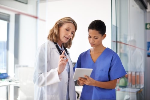 Female physician and nurse discussing medical information