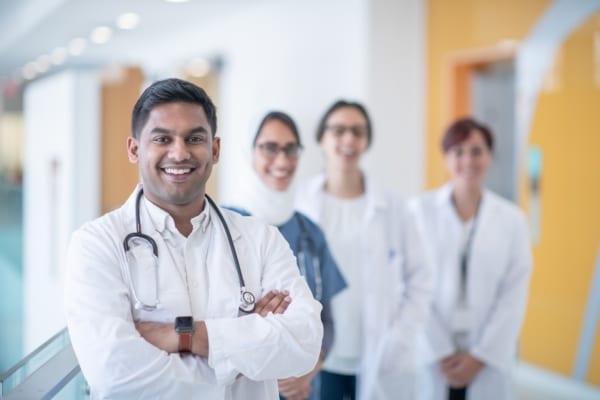 Smiling medical student with his colleagues at the hospital