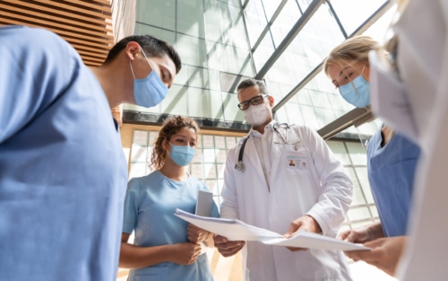 Group of doctors and nurses talking at the hospital while wearing facemasks