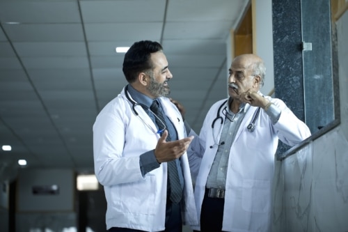 Two male doctors discussing at hospital corridor